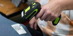 A handheld barcode scanner being used to scan an order label