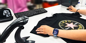 A decorated black t-shirt at a workstation with a keyboard and barcode scanner
